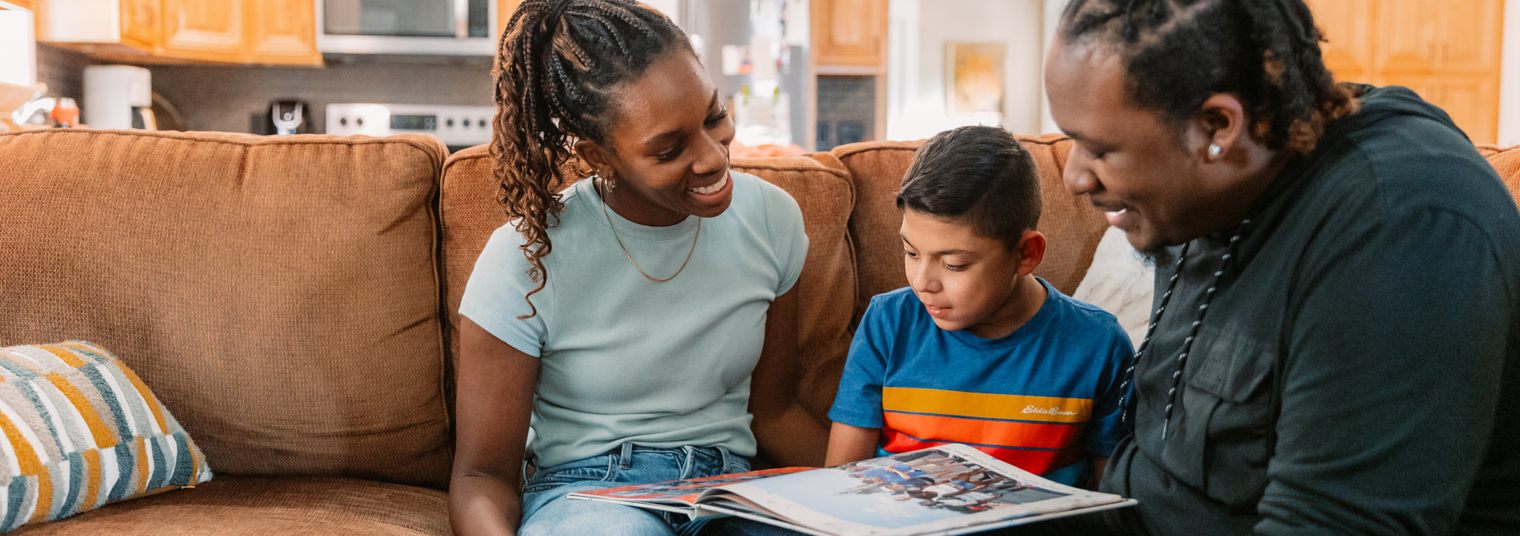 An African American adoptive family looks at their son's adoption photo book